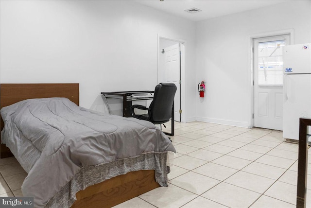 bedroom with visible vents, baseboards, light tile patterned flooring, and freestanding refrigerator