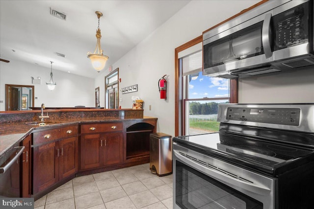 kitchen featuring visible vents, lofted ceiling, a sink, stainless steel appliances, and decorative light fixtures