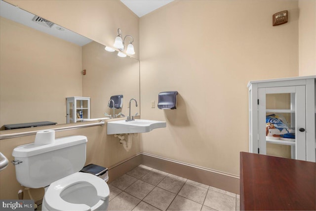 half bathroom featuring tile patterned floors, toilet, a sink, baseboards, and a chandelier