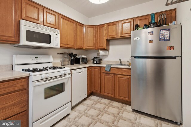 kitchen with sink, white appliances, and light tile patterned floors