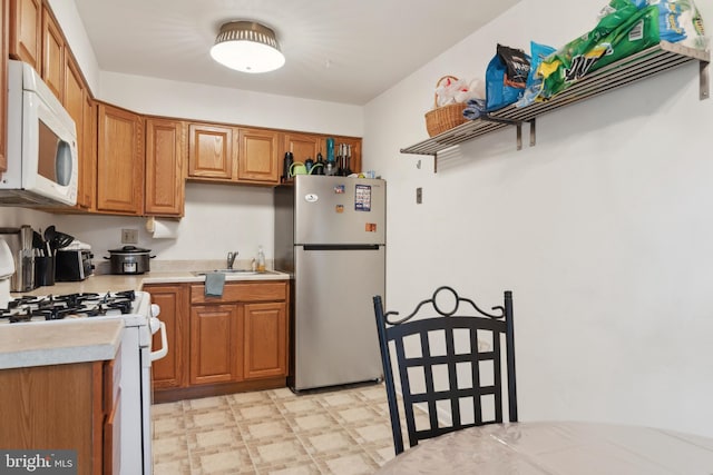 kitchen with sink, white appliances, and light tile patterned floors