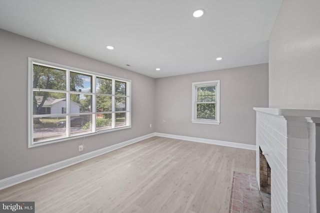 unfurnished living room with a brick fireplace and light hardwood / wood-style floors