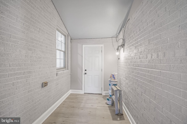 clothes washing area featuring brick wall and light hardwood / wood-style flooring