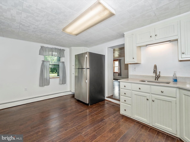 kitchen with white cabinetry, dark wood-type flooring, stainless steel refrigerator, sink, and a baseboard heating unit