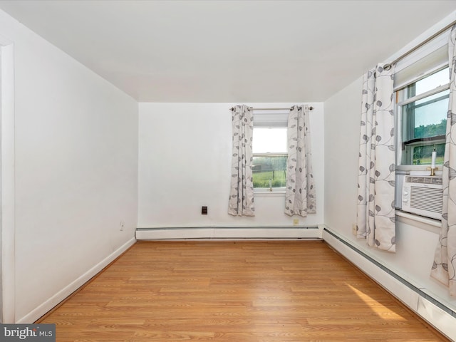 unfurnished room featuring plenty of natural light, light hardwood / wood-style floors, and a baseboard heating unit