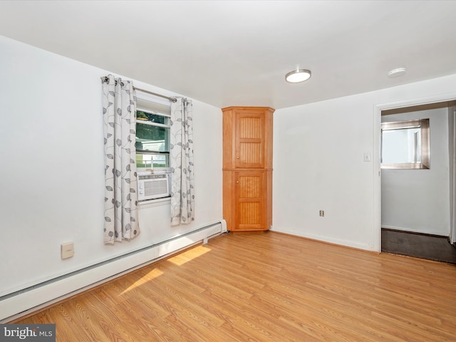 spare room with baseboard heating and light wood-type flooring