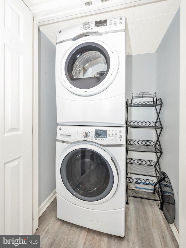 clothes washing area with light hardwood / wood-style floors and stacked washing maching and dryer