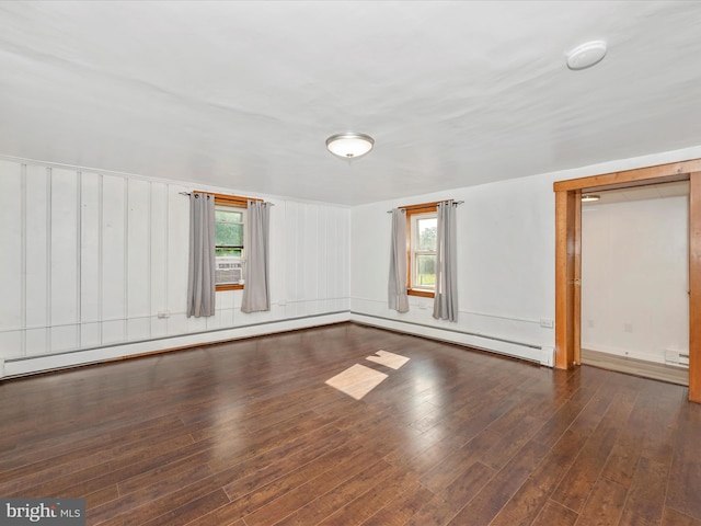 empty room featuring baseboard heating and dark hardwood / wood-style flooring