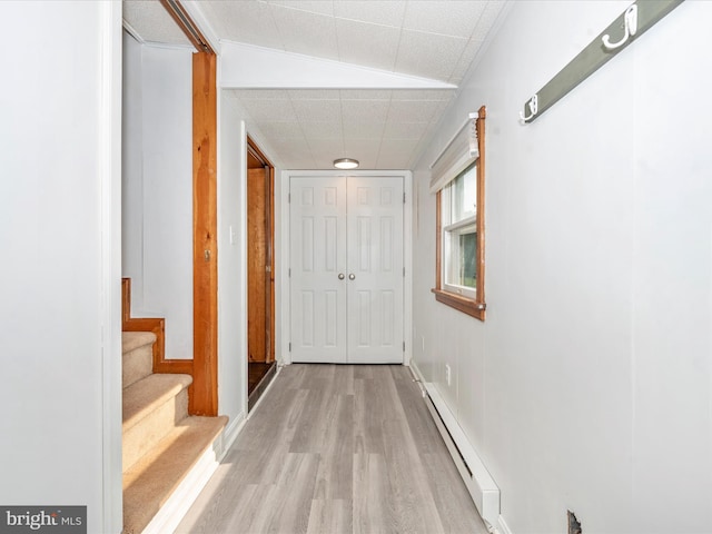 hallway with a baseboard radiator, lofted ceiling, and light hardwood / wood-style flooring