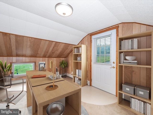 home office with a baseboard radiator, vaulted ceiling, wood walls, and light carpet