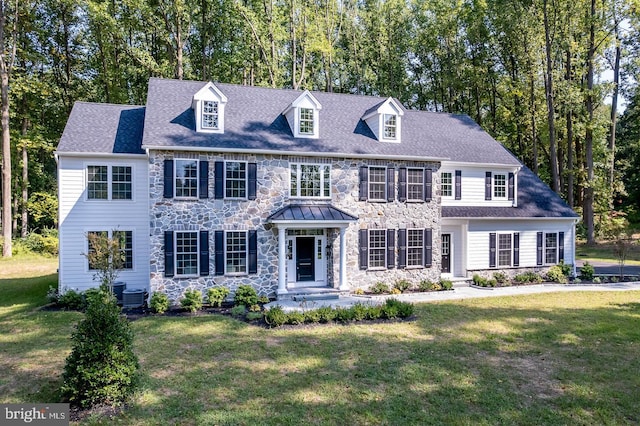 colonial home featuring central AC unit and a front yard