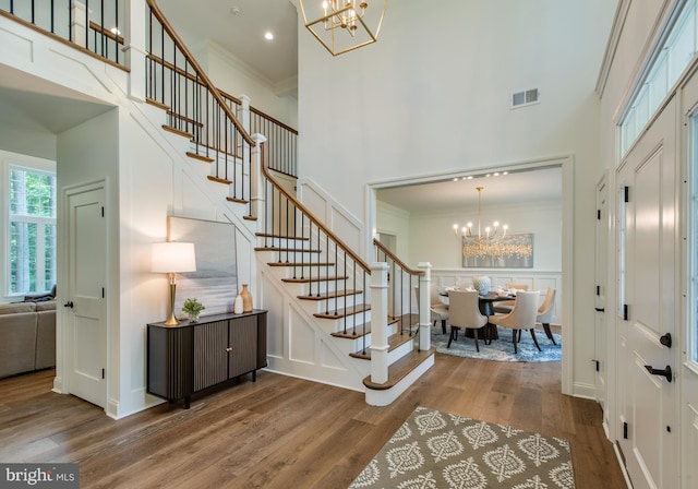 foyer entrance featuring an inviting chandelier, crown molding, a high ceiling, and hardwood / wood-style floors