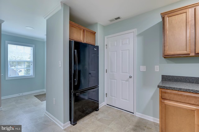 kitchen with visible vents, baseboards, freestanding refrigerator, dark countertops, and crown molding