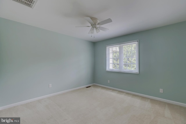 empty room with baseboards, a ceiling fan, visible vents, and light colored carpet