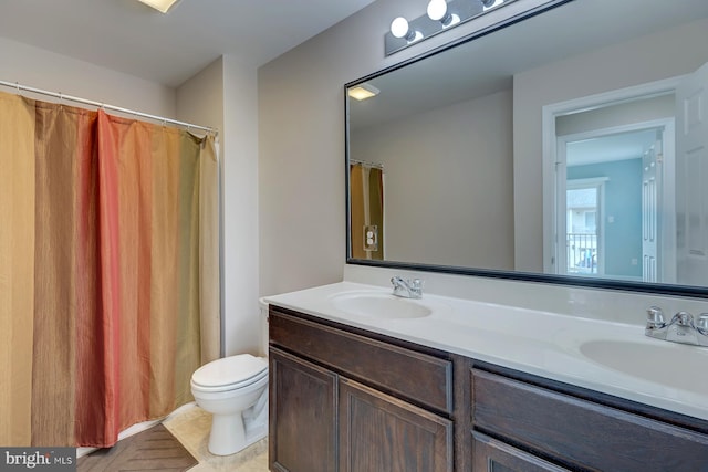 full bath featuring double vanity, toilet, a sink, and tile patterned floors