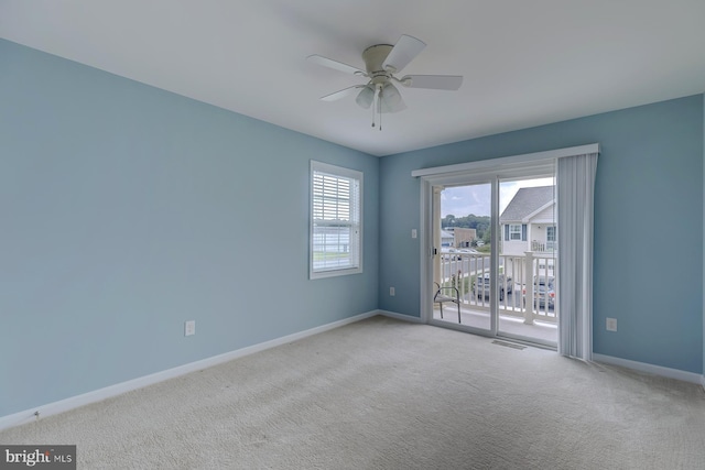 spare room featuring light carpet, ceiling fan, visible vents, and baseboards