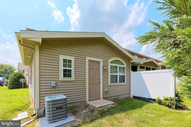 exterior space featuring fence, a front lawn, and central AC unit