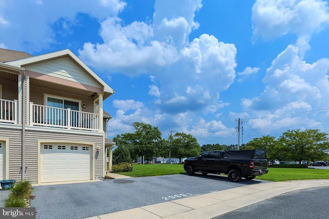 view of home's exterior with a garage, a yard, and a balcony