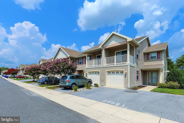 multi unit property featuring driveway, a balcony, an attached garage, and a residential view