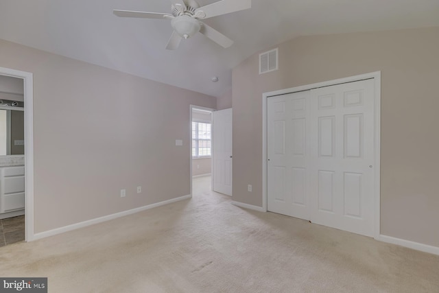 unfurnished bedroom featuring baseboards, visible vents, vaulted ceiling, and light colored carpet