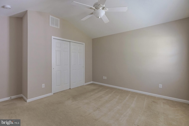 unfurnished bedroom with a closet, visible vents, light carpet, vaulted ceiling, and baseboards