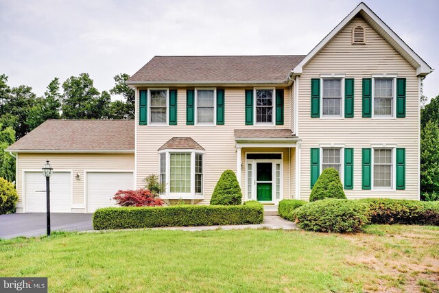 colonial house featuring a front lawn and a garage