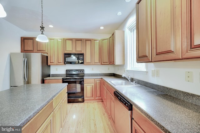 kitchen featuring sink, decorative light fixtures, light hardwood / wood-style floors, and black appliances