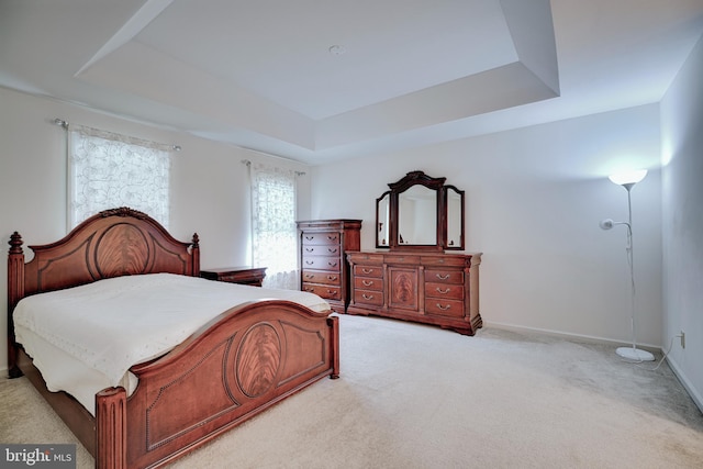 bedroom with a tray ceiling and light carpet