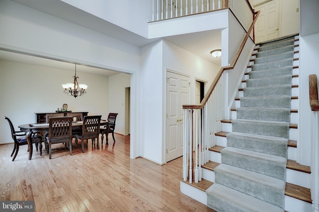 interior space with a towering ceiling, a notable chandelier, and light wood-type flooring