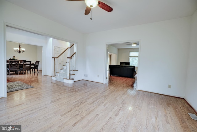 living room featuring ceiling fan with notable chandelier and hardwood / wood-style flooring