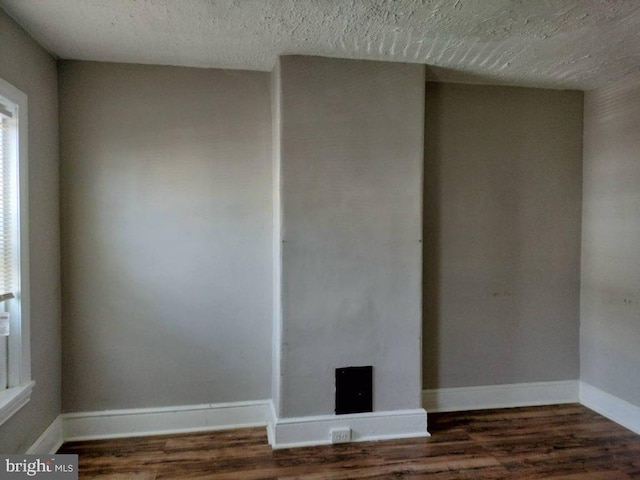 unfurnished living room featuring a textured ceiling and dark hardwood / wood-style flooring