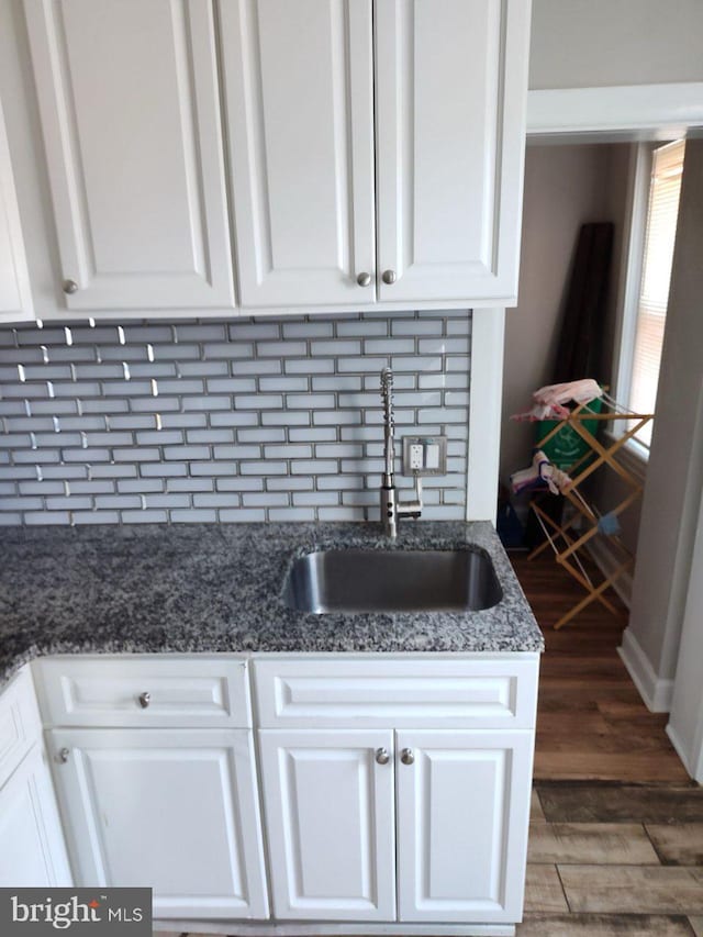 kitchen with dark hardwood / wood-style floors, dark stone counters, sink, and white cabinets