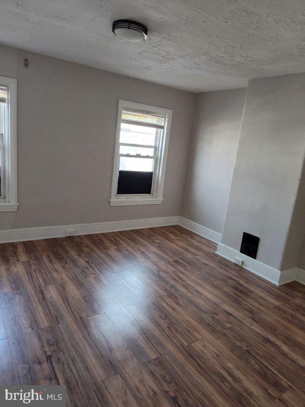 unfurnished room with a textured ceiling and dark hardwood / wood-style flooring