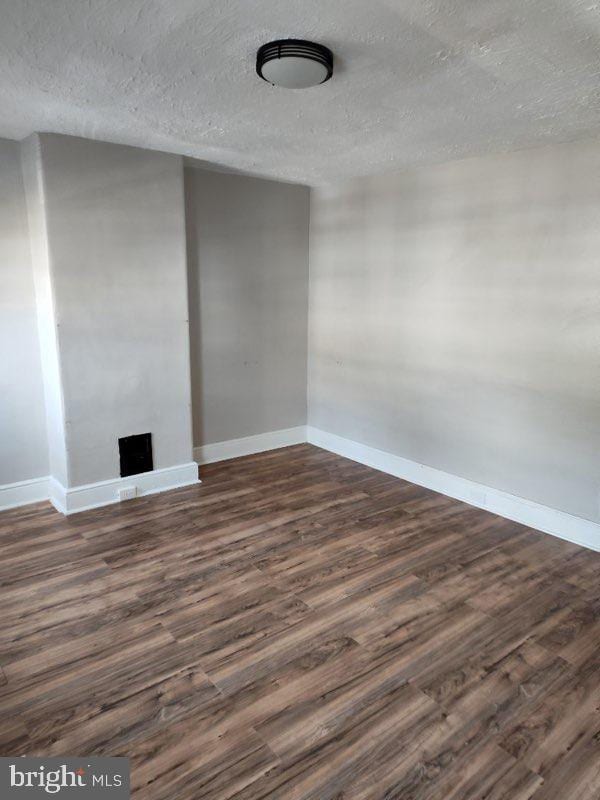 unfurnished room featuring a textured ceiling and dark hardwood / wood-style floors