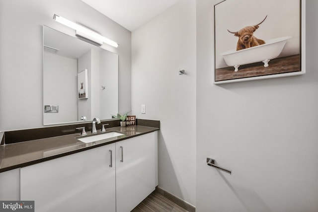 bathroom featuring visible vents, vanity, baseboards, and wood finished floors