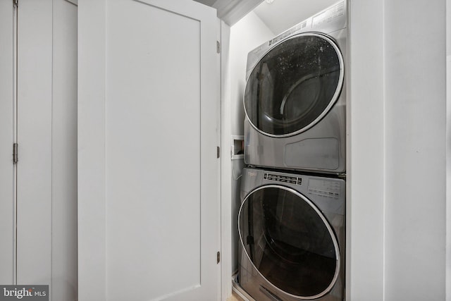 washroom featuring stacked washer / dryer and laundry area