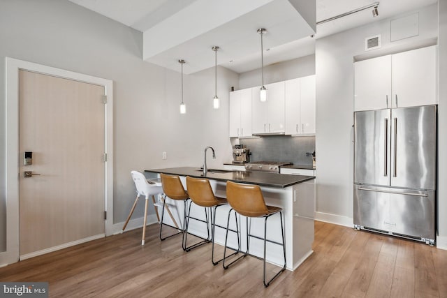 kitchen with appliances with stainless steel finishes, dark countertops, white cabinetry, and hanging light fixtures