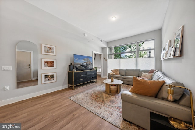 living room featuring light wood-type flooring, visible vents, and baseboards