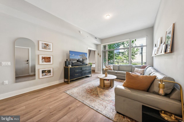 living room featuring visible vents, light wood-style flooring, and baseboards