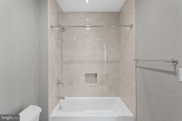 bathroom with tiled shower / bath combo and toilet