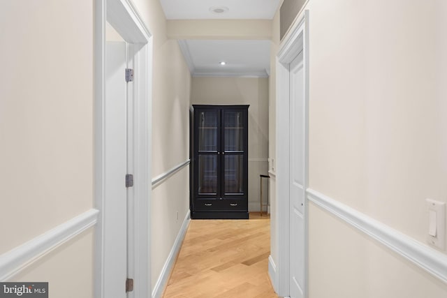 hall with ornamental molding and light hardwood / wood-style floors