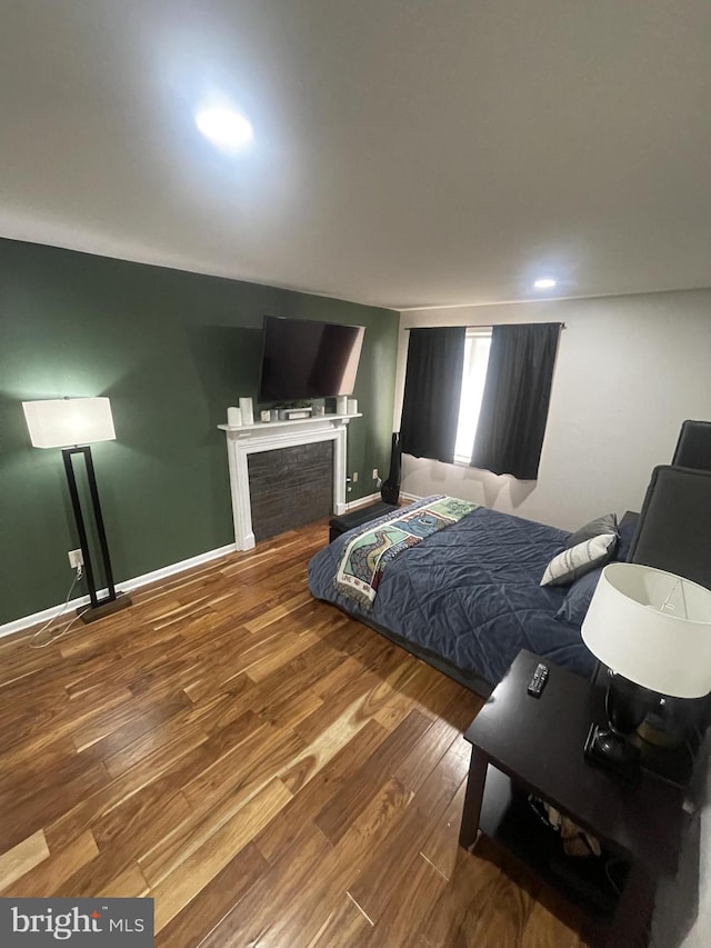 bedroom with a fireplace, baseboards, and wood finished floors