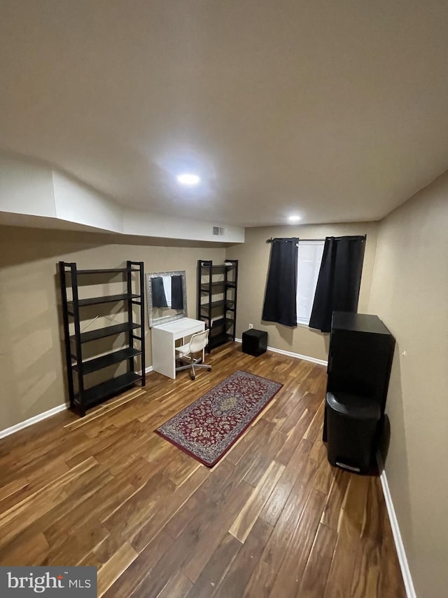 living area with visible vents, baseboards, and wood finished floors