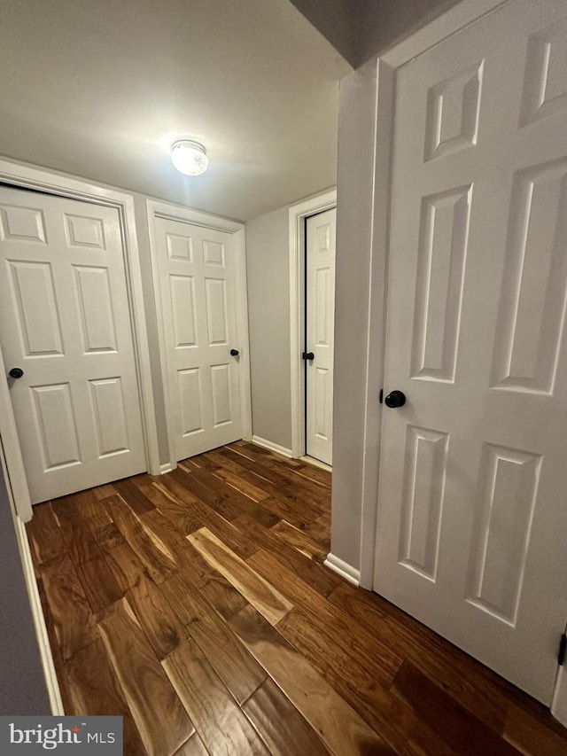 hallway with dark wood finished floors and baseboards