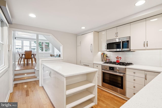 kitchen featuring backsplash, light hardwood / wood-style floors, white cabinetry, and stainless steel appliances