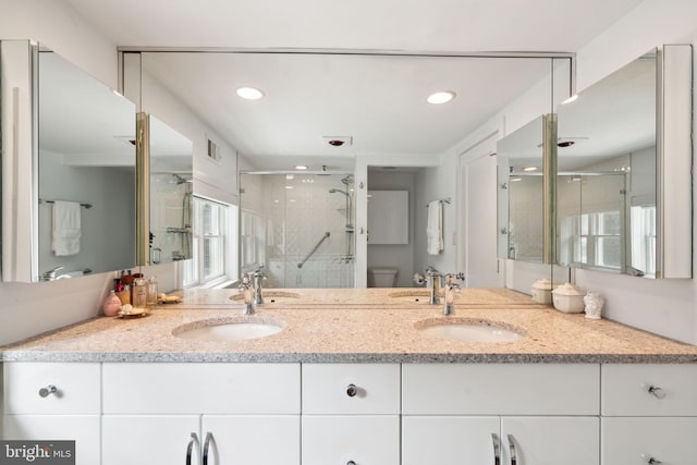 bathroom featuring vanity, toilet, and a shower with shower door