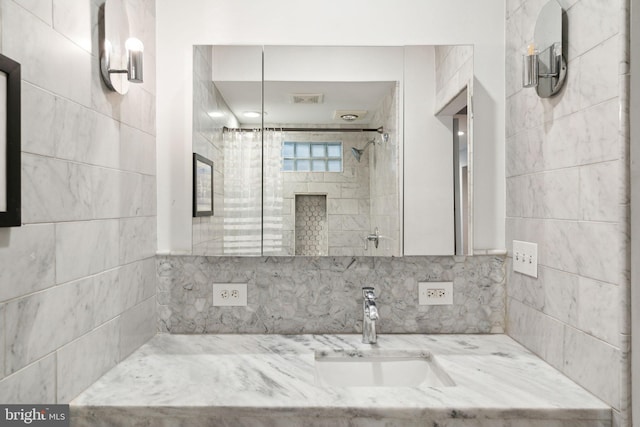 bathroom with a tile shower and sink