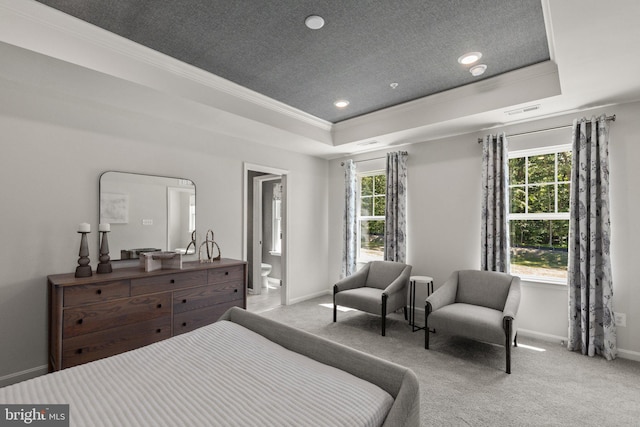 carpeted bedroom with a tray ceiling, crown molding, and ensuite bath