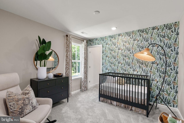 carpeted bedroom featuring a nursery area