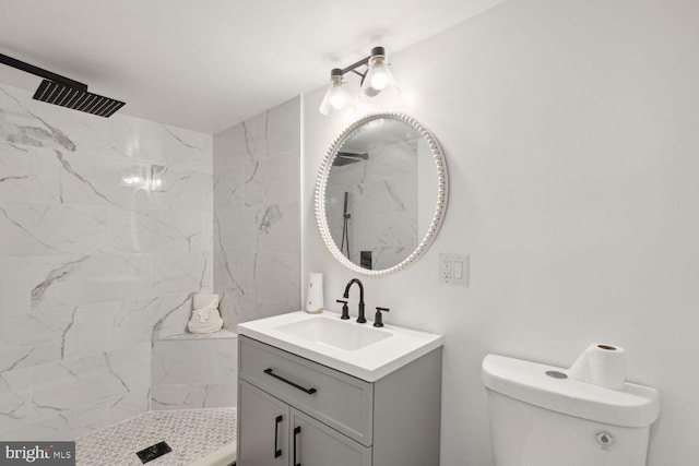 bathroom featuring toilet, a tile shower, and vanity